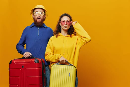 Woman and man smiling, suitcases in hand with yellow and red suitcase smiling merrily and crooked, yellow background, going on a trip, family vacation trip, newlyweds. High quality photo