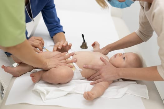 Baby beeing vaccinated by pediatrician in presence of his mother. Preventive vaccination against Diphtheria, whooping cough, tetanus, hepatitis, haemophilus influenzae, pneumococcus, poliomyelitis.