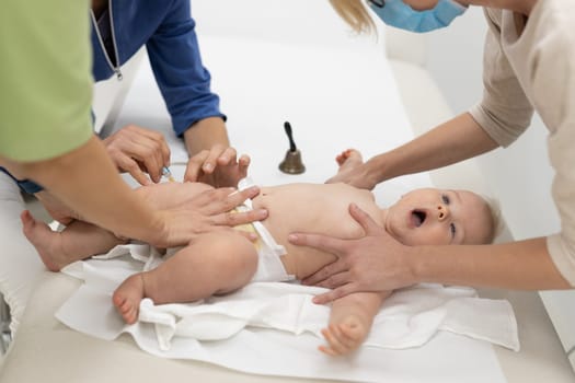 Baby beeing vaccinated by pediatrician in presence of his mother. Preventive vaccination against Diphtheria, whooping cough, tetanus, hepatitis, haemophilus influenzae, pneumococcus, poliomyelitis.