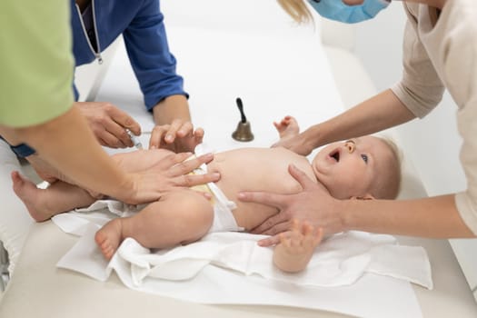 Baby beeing vaccinated by pediatrician in presence of his mother. Preventive vaccination against Diphtheria, whooping cough, tetanus, hepatitis, haemophilus influenzae, pneumococcus, poliomyelitis.