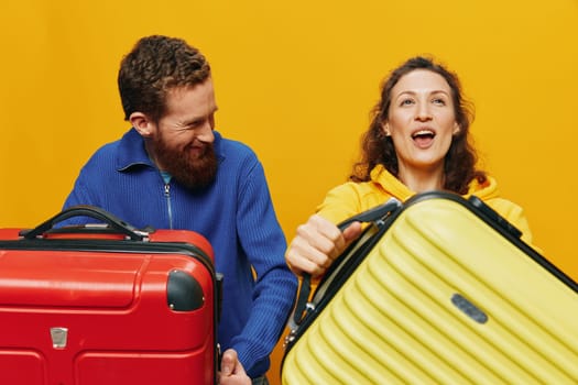 Woman and man smiling, suitcases in hand with yellow and red suitcase smiling merrily and crooked, yellow background, going on a trip, family vacation trip, newlyweds. High quality photo