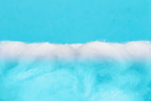 Soft gentle background from white cotton wool and blue paper.Conceptual sea from above.