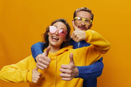 Man and woman couple smiling cheerfully and crooked with glasses, on yellow background, symbols signs and hand gestures, family shoot, newlyweds. High quality photo