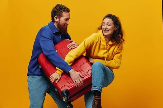 Woman and man smiling, suitcases in hand with yellow and red suitcase smiling merrily and crooked, yellow background, going on a trip, family vacation trip, newlyweds. High quality photo