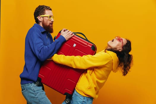 Woman and man smiling, suitcases in hand with yellow and red suitcase smiling merrily and crooked, yellow background, going on a trip, family vacation trip, newlyweds. High quality photo