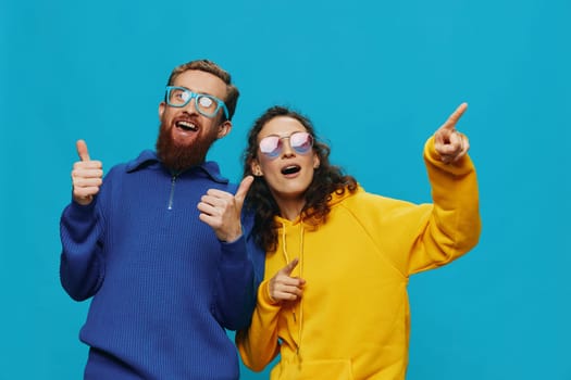 A woman and a man fun couple cranking and showing signs with their hands smiling cheerfully, on a blue background, The concept of a real relationship in a family. High quality photo