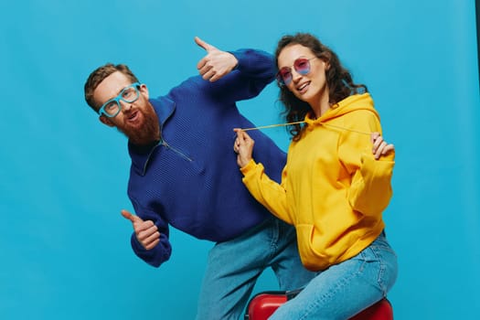 Woman and man smile sitting on suitcase with red suitcase smile, on blue background, packing for trip, family vacation trip. High quality photo