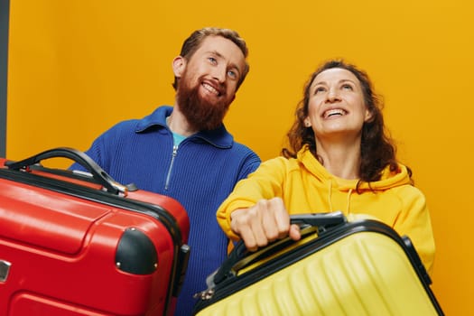 Woman and man smiling, suitcases in hand with yellow and red suitcase smiling merrily and crooked, yellow background, going on a trip, family vacation trip, newlyweds. High quality photo