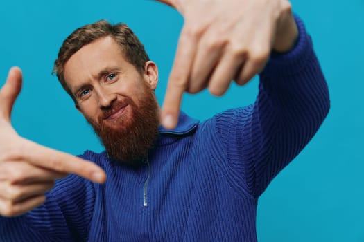 Portrait of a man in a sweater smile and happiness, hand signs and symbols, on a blue background. Lifestyle positive, copy place. High quality photo