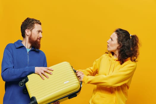 Woman and man smiling, suitcases in hand with yellow and red suitcase smiling merrily and crooked, yellow background, going on a trip, family vacation trip, newlyweds. High quality photo