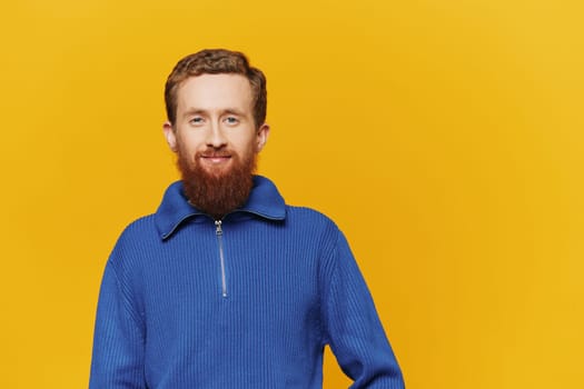 Portrait of a man smiling in a blue sweater on a yellow background copy space, space for text. High quality photo