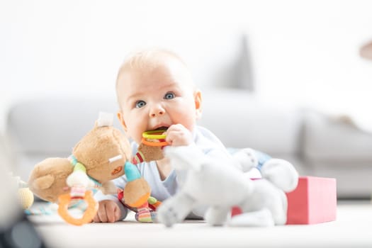 Cute baby boy playing with toys on mat at home Baby activity and play center for early infant development. Baby playing at home