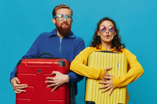 Woman and man smile suitcases in hand with yellow and red suitcase smile fun, on blue background, packing for a trip, family vacation trip. High quality photo