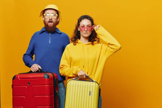 Woman and man smiling, suitcases in hand with yellow and red suitcase smiling merrily and crooked, yellow background, going on a trip, family vacation trip, newlyweds. High quality photo