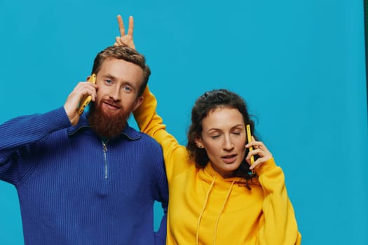 Woman and man cheerful couple with phones in their hands crooked smile cheerful, on blue background. The concept of real family relationships, talking on the phone, work online. High quality photo