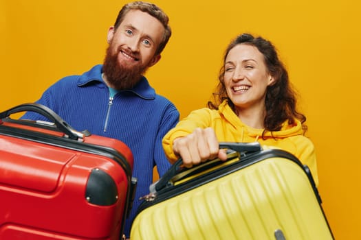 Woman and man smiling, suitcases in hand with yellow and red suitcase smiling merrily and crooked, yellow background, going on a trip, family vacation trip, newlyweds. High quality photo