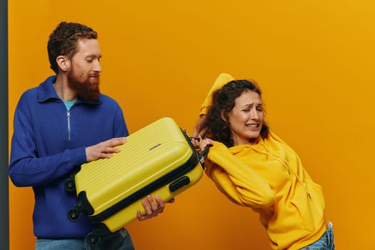 Woman and man smiling, suitcases in hand with yellow and red suitcase smiling merrily and crooked, yellow background, going on a trip, family vacation trip, newlyweds. High quality photo