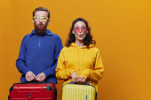 Woman and man smiling, suitcases in hand with yellow and red suitcase smiling merrily and crooked, yellow background, going on a trip, family vacation trip, newlyweds. High quality photo