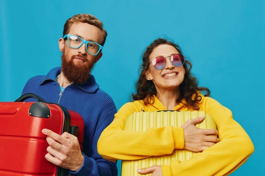 Woman and man smile suitcases in hand with yellow and red suitcase smile fun, on blue background, packing for a trip, family vacation trip. High quality photo