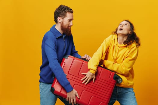 Woman and man smiling, suitcases in hand with yellow and red suitcase smiling merrily and crooked, yellow background, going on a trip, family vacation trip, newlyweds. High quality photo