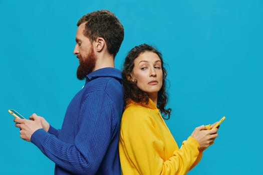 Woman and man cheerful couple with phones in their hands crooked smile cheerful, on blue background. The concept of real family relationships, talking on the phone, work online. High quality photo