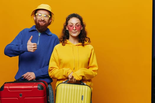 Woman and man smiling, suitcases in hand with yellow and red suitcase smiling merrily and crooked, yellow background, going on a trip, family vacation trip, newlyweds. High quality photo