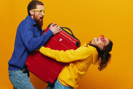 Woman and man smiling, suitcases in hand with yellow and red suitcase smiling merrily and crooked, yellow background, going on a trip, family vacation trip, newlyweds. High quality photo