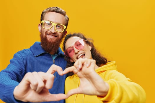 Man and woman couple smiling cheerfully and crooked with glasses, on yellow background, symbols signs and hand gestures, family shoot, newlyweds. High quality photo