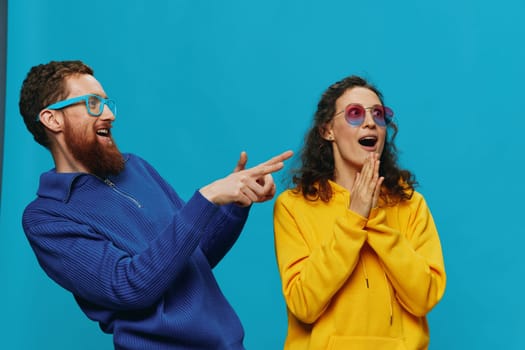 A woman and a man fun couple cranking and showing signs with their hands smiling cheerfully, on a blue background, The concept of a real relationship in a family. High quality photo