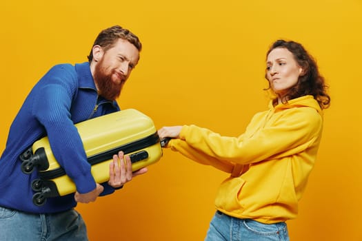 Woman and man smiling, suitcases in hand with yellow and red suitcase smiling merrily and crooked, yellow background, going on a trip, family vacation trip, newlyweds. High quality photo