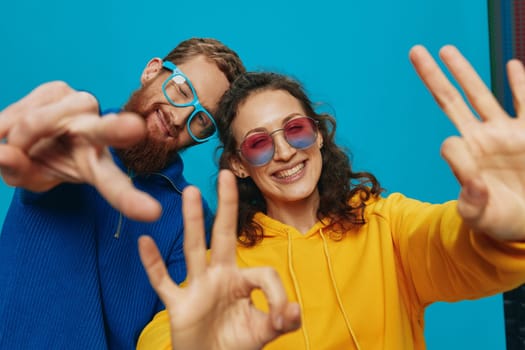 A woman and a man fun couple cranking and showing signs with their hands smiling cheerfully, on a blue background, The concept of a real relationship in a family. High quality photo