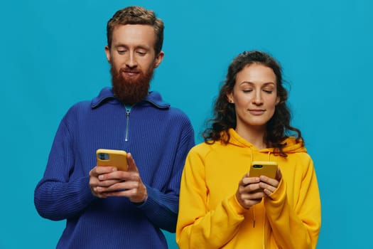 Woman and man cheerful couple with phones in their hands crooked smile cheerful, on blue background. The concept of real family relationships, talking on the phone, work online. High quality photo