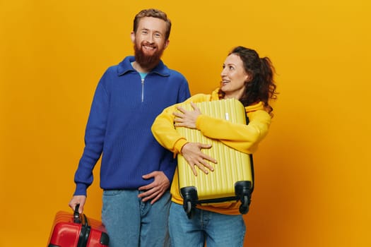 Woman and man smiling, suitcases in hand with yellow and red suitcase smiling merrily and crooked, yellow background, going on a trip, family vacation trip, newlyweds. High quality photo