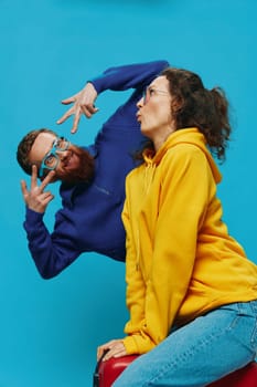 Woman and man smile sitting on suitcase with red suitcase smile, on blue background, packing for trip, family vacation trip. High quality photo