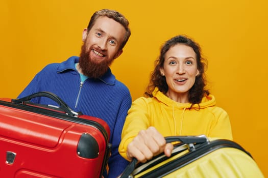 Woman and man smiling, suitcases in hand with yellow and red suitcase smiling merrily and crooked, yellow background, going on a trip, family vacation trip, newlyweds. High quality photo