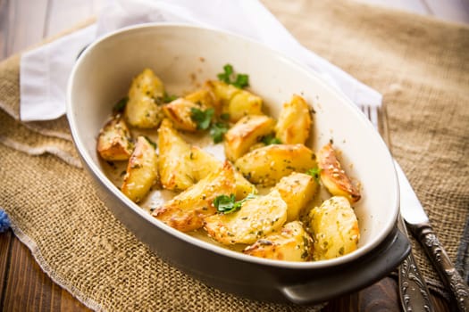 potatoes baked with sesame seeds, herbs and spices in the oven in a ceramic form.