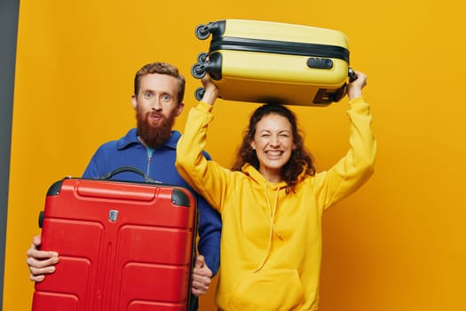 Woman and man smiling, suitcases in hand with yellow and red suitcase smiling merrily and crooked, yellow background, going on a trip, family vacation trip, newlyweds. High quality photo