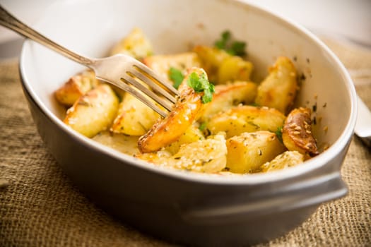 potatoes baked with sesame seeds, herbs and spices in the oven in a ceramic form.