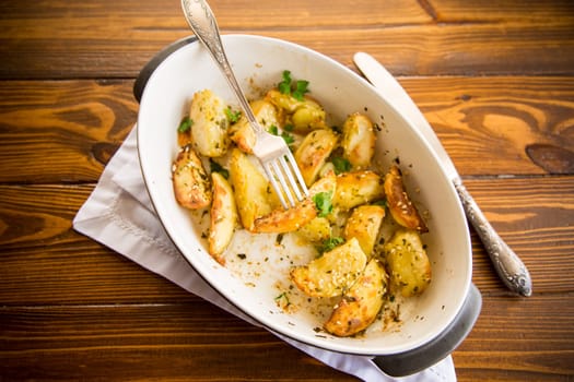 potatoes baked with sesame seeds, herbs and spices in the oven in a ceramic form.