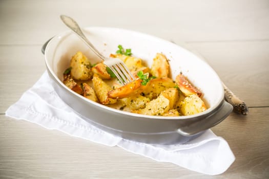 potatoes baked with sesame seeds, herbs and spices in the oven in a ceramic form.