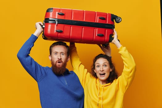 Woman and man smiling, suitcases in hand with yellow and red suitcase smiling merrily and crooked, yellow background, going on a trip, family vacation trip, newlyweds. High quality photo