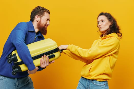 Woman and man smiling, suitcases in hand with yellow and red suitcase smiling merrily and crooked, yellow background, going on a trip, family vacation trip, newlyweds. High quality photo