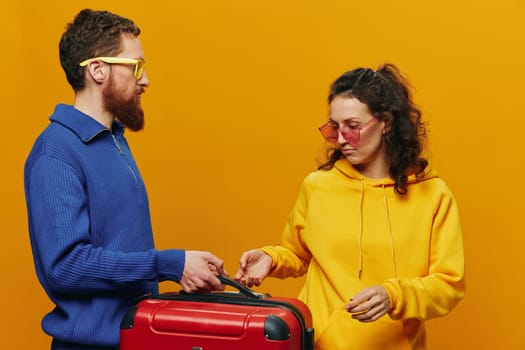 Woman and man smiling, suitcases in hand with yellow and red suitcase smiling merrily and crooked, yellow background, going on a trip, family vacation trip, newlyweds. High quality photo