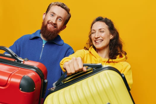 Woman and man smiling, suitcases in hand with yellow and red suitcase smiling merrily and crooked, yellow background, going on a trip, family vacation trip, newlyweds. High quality photo