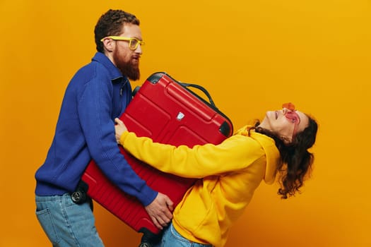 Woman and man smiling, suitcases in hand with yellow and red suitcase smiling merrily and crooked, yellow background, going on a trip, family vacation trip, newlyweds. High quality photo