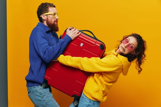 Woman and man smiling, suitcases in hand with yellow and red suitcase smiling merrily and crooked, yellow background, going on a trip, family vacation trip, newlyweds. High quality photo