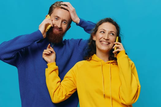 Woman and man cheerful couple with phones in their hands crooked smile cheerful, on blue background. The concept of real family relationships, talking on the phone, work online. High quality photo