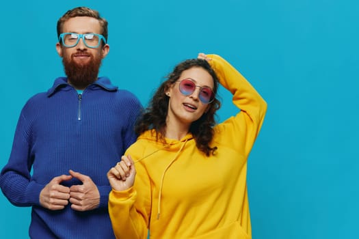 A woman and a man fun couple cranking and showing signs with their hands smiling cheerfully, on a blue background, The concept of a real relationship in a family. High quality photo