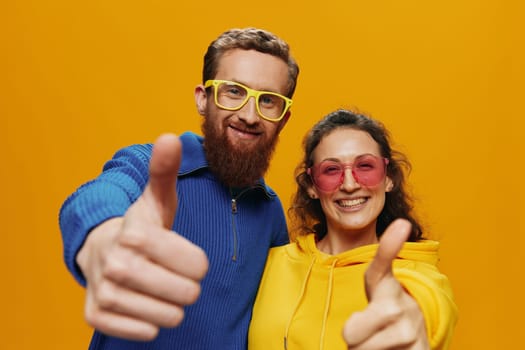 Man and woman couple smiling cheerfully and crooked with glasses, on yellow background, symbols signs and hand gestures, family shoot, newlyweds. High quality photo