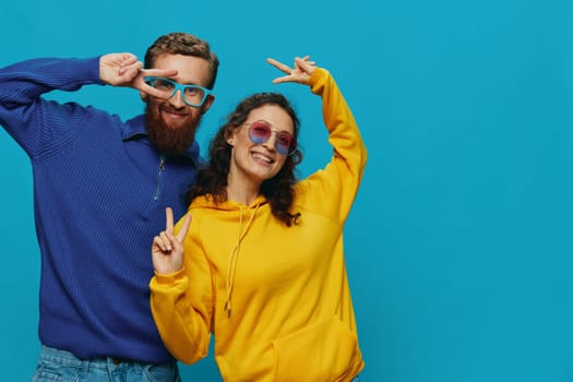 A woman and a man fun couple cranking and showing signs with their hands smiling cheerfully, on a blue background, The concept of a real relationship in a family. High quality photo